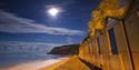 Night time view with the moon shining over the beach huts at Shanklln beach, Things to Do, Isle of Wight