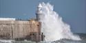 Wave crashing over lighthouse on harbour arm at Folkestone