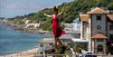 Lady walking along a tightrope with the sea in the background in Ventnor on the Isle of Wight