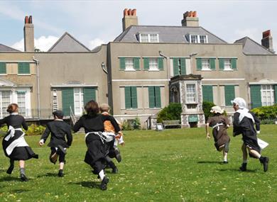 Children in historic dress running on lawn