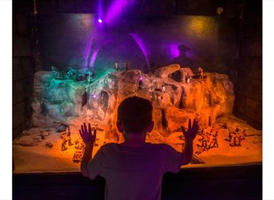 Child looking at a miniature model of smugglers using the caves, at Smugglers adventure Hastings