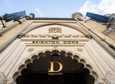 The exterior main entrance of Brighton Dome, the shot is taken looking up toward the Dome sign above an intricate doorway.