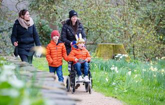 Two women walking with two children in orange jackets, one of whom is in a wheelchair, taking part in the Easter trail