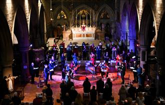 Singers of Hastings Philharmonic Orchestra on stage under coloured lights.