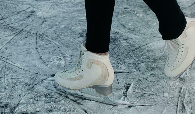 Person in white figure skates on fresh ice Person in white figure skates on fresh ice