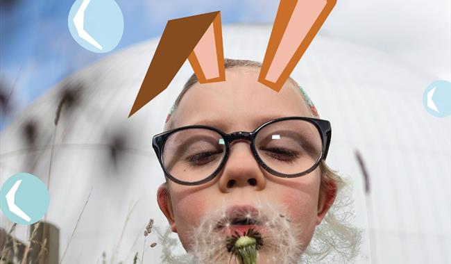 A little girl with illustrated bunny ears blows a dandelion