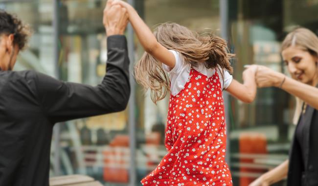 A child in a red dress with their parents A child in a red dress with their parents