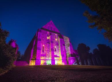 Battle Abbey illuminated at night in purple