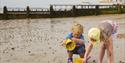Image of two children, bucket & spade on the beach