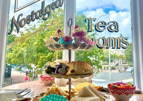 full cake stand in front of a window with Nostalgia Tea Rooms written on the window in cursive lettering