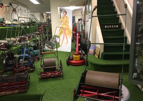 interior of a museum with artificial grass and a display of vintage lawnmowers
