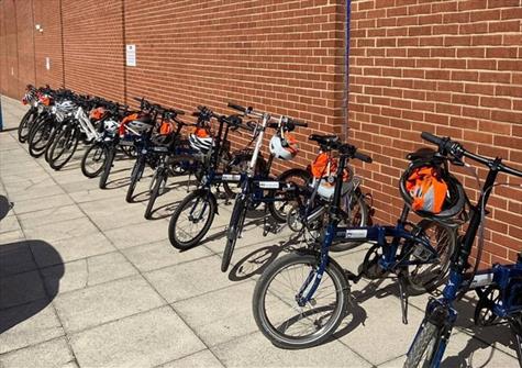 a row of bikes standing in front of a long brick wall