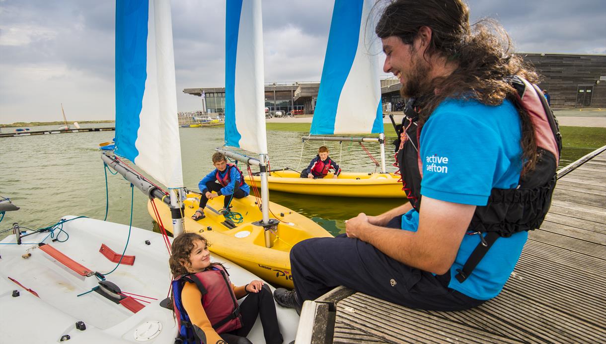 An instructor talking to a young girl who's sat on a boat