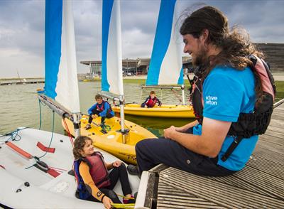 An instructor talking to a young girl who's sat on a boat