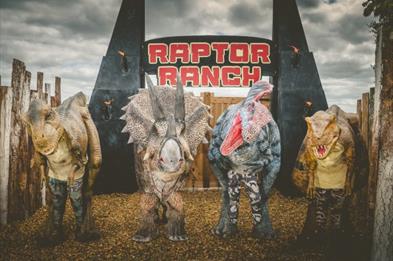 Four dinosaurs stand outside the Raptor Ranch at the National Forest Adventure Farm