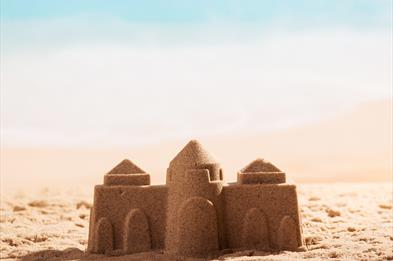 Image shows a sandcastle on a beach
