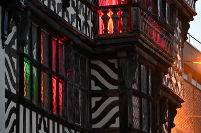 Image shows the Ancient High House in Stafford, with spooky green and red lights shining out from inside