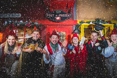 Image shows some of the performers from North Pole Adventure, in costumes, as snow falls down