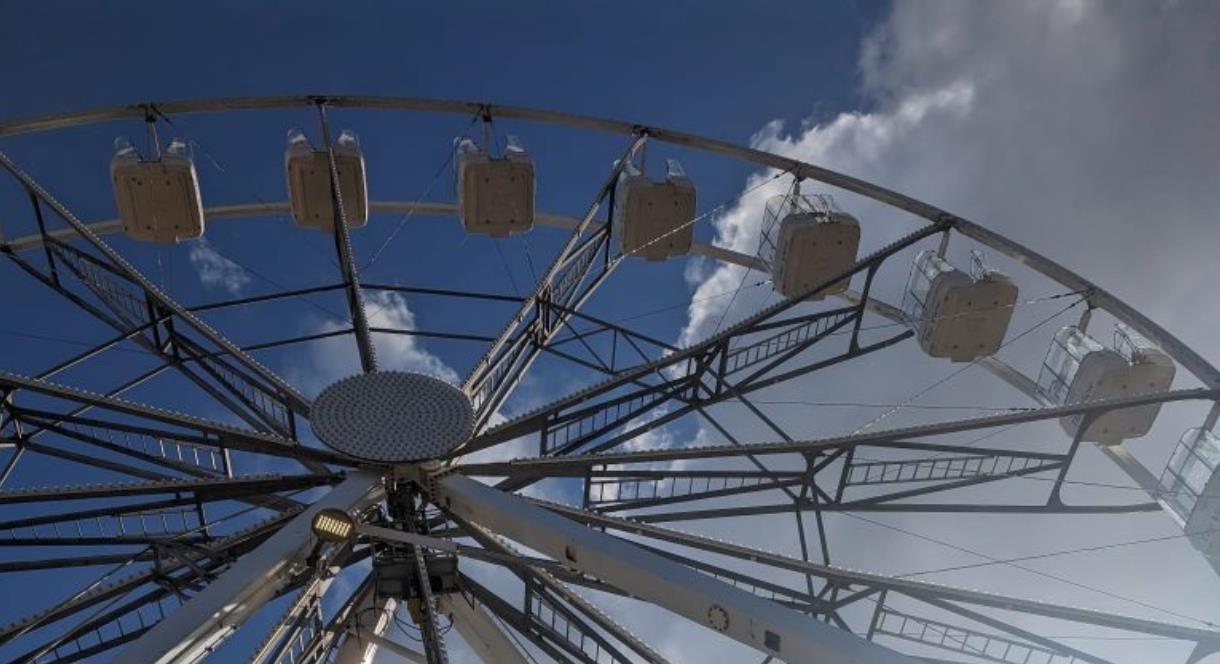 A ferris wheel against a blue sky with white fluffy clouds