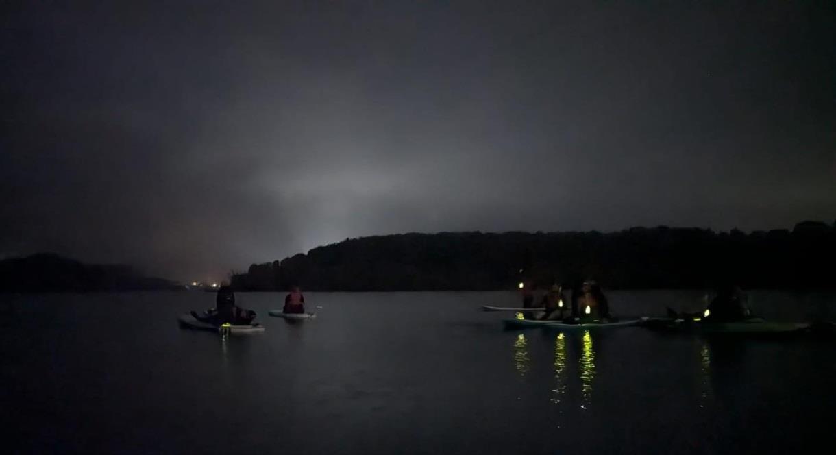 image of paddle boarders at nigh time with headlights