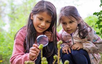 image of 2 girls with a magnifying glass