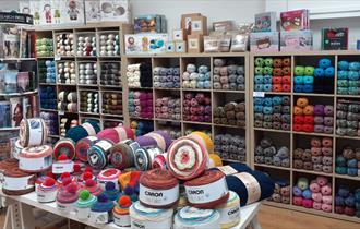 image of shop interior, shelves with different colours of yarn