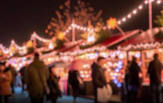 Image shows a market with Christmas lights and people browsing
