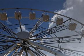 A ferris wheel against a blue sky with white fluffy clouds