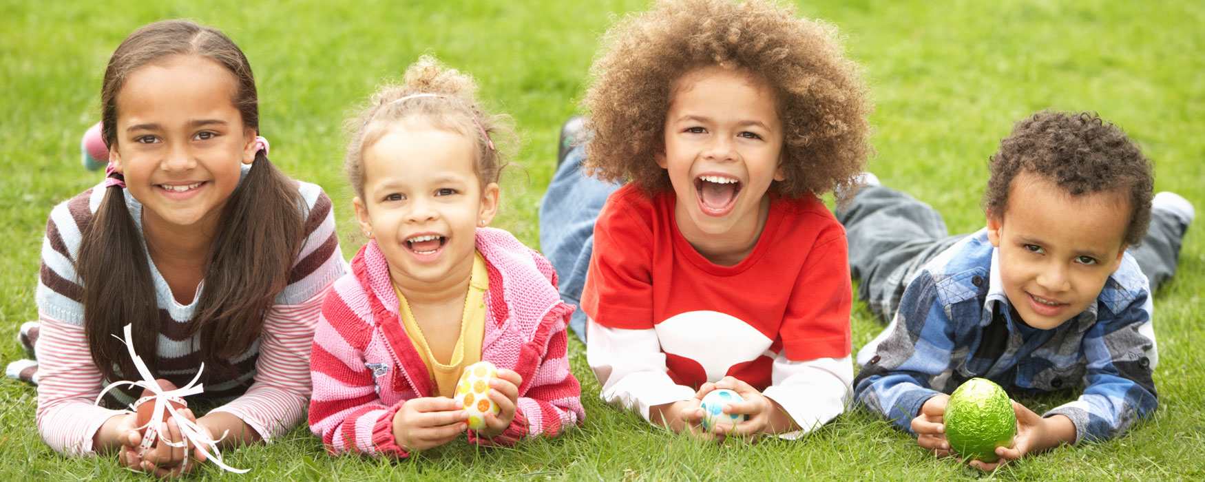 Children laid on grass with Easter eggs. Click to read more about things to do for Easter in Staffordshire.