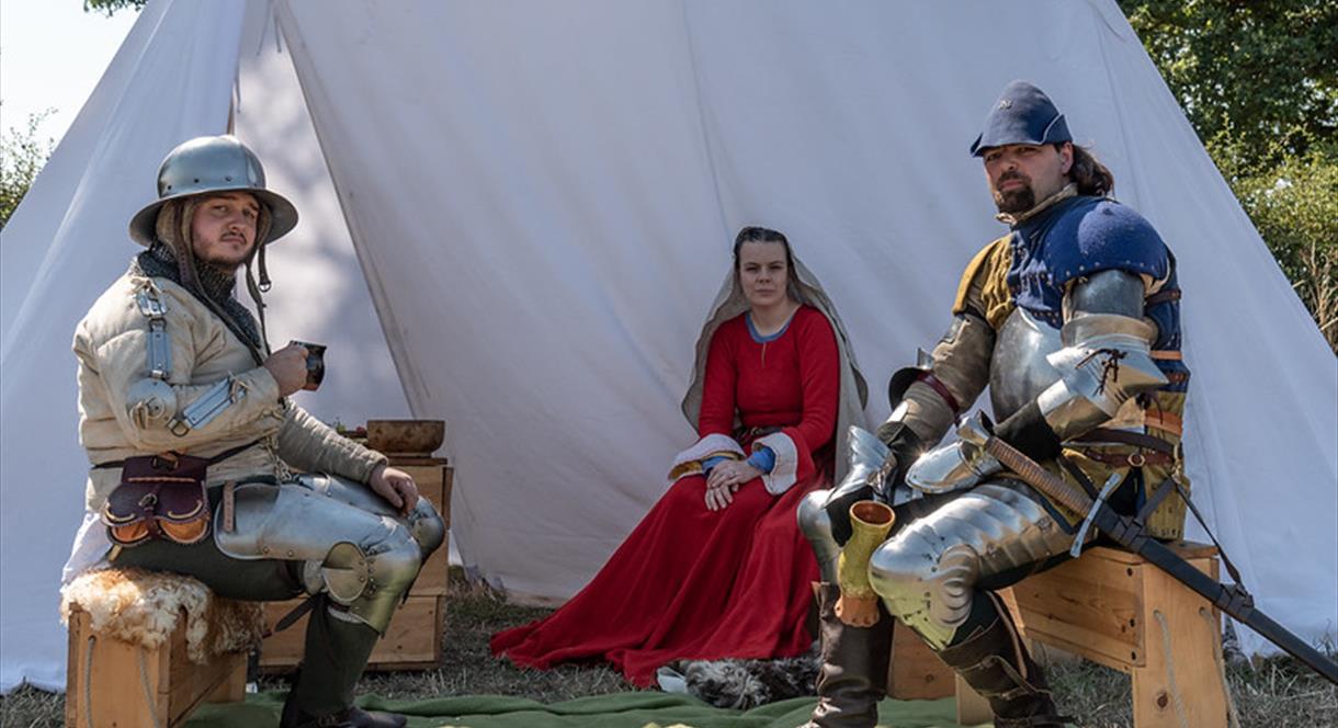 Three actors in medieval costumes prepare for a photography workshop
