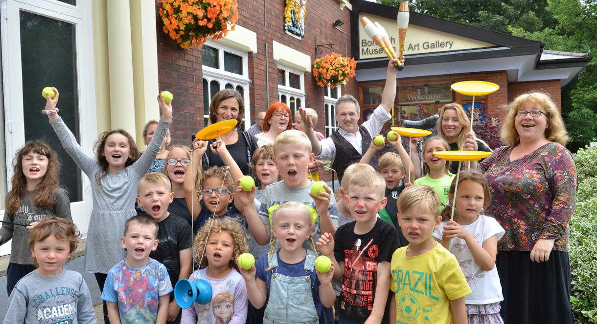 A group of children and adults with circus skills equipment   including balls and plates