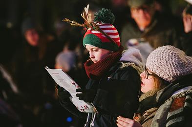 A festive looking family sing Christmas carols at the National Memorial Arboretum, Staffordshire