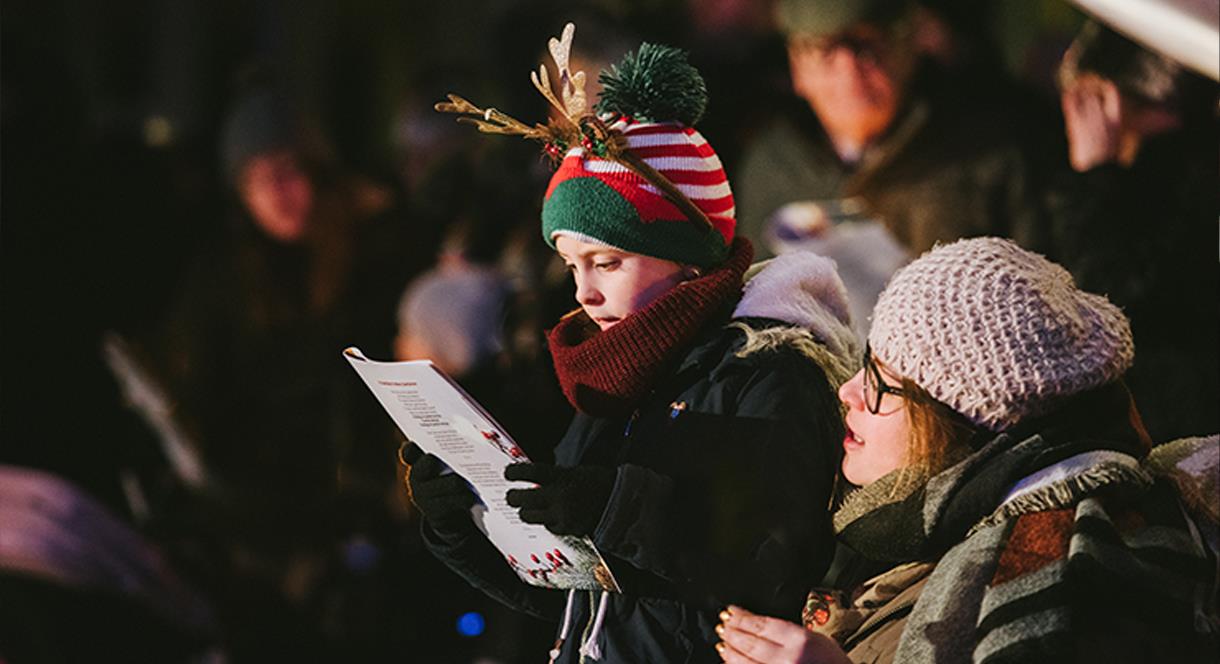 A festive looking family sing Christmas carols at the National Memorial Arboretum, Staffordshire