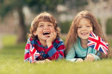 Two children lie on the grass with their British flags