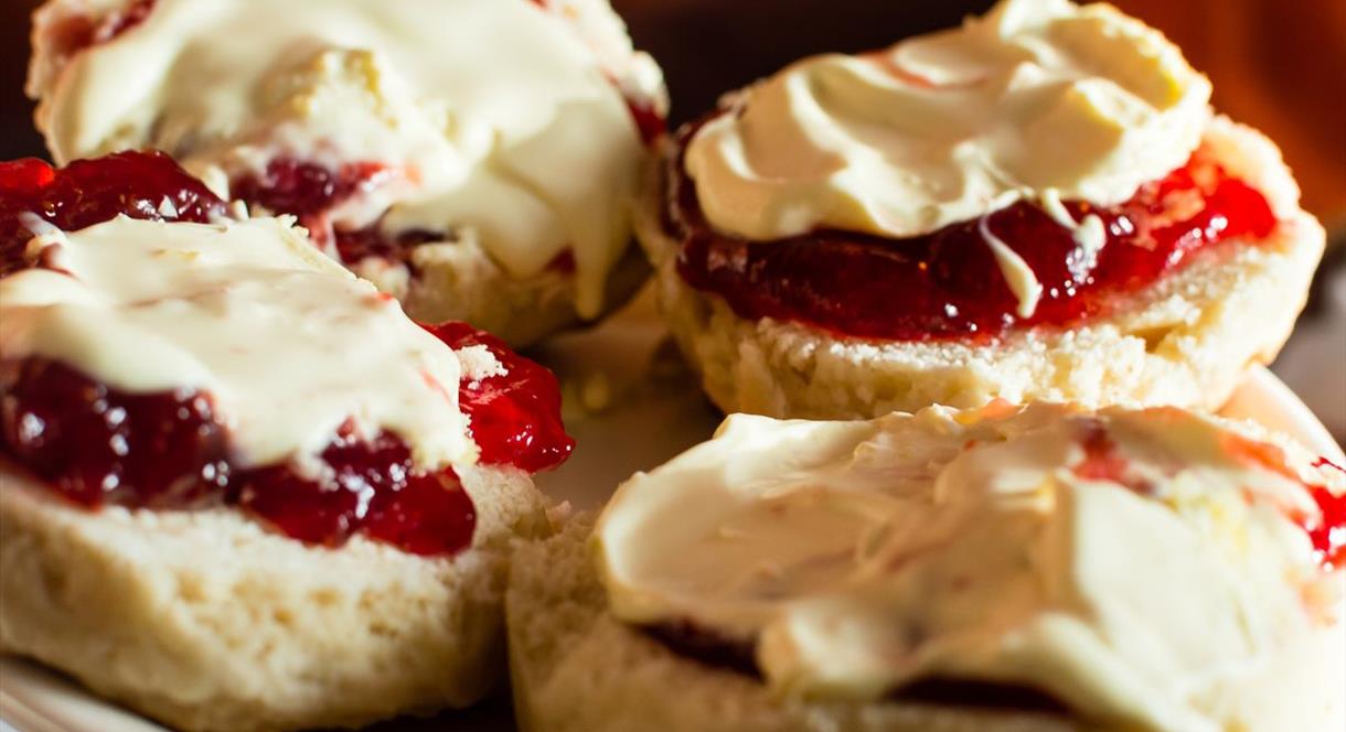 A mouth-watering image of scones with jam and cream