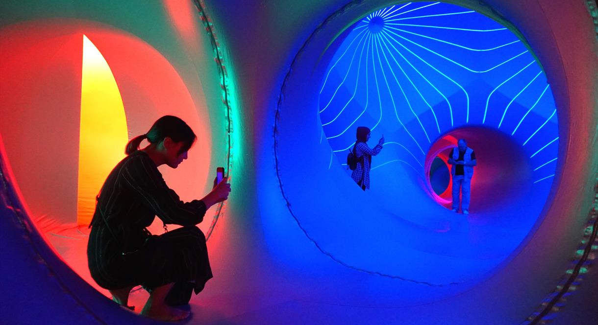 Visitors immerse themselves in the colourful, illuminated tunnels of The Luminarium, an interactive walk-in sculpture.