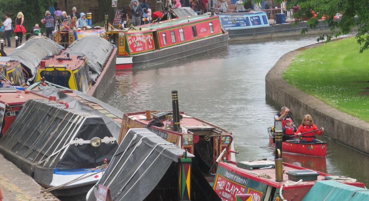 Image shows canal boats moored up, selling their wares to canal festival visitors