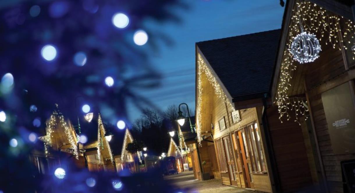 Timber lodges with Christmas lights at Trentham Shopping Village, Staffordshire
