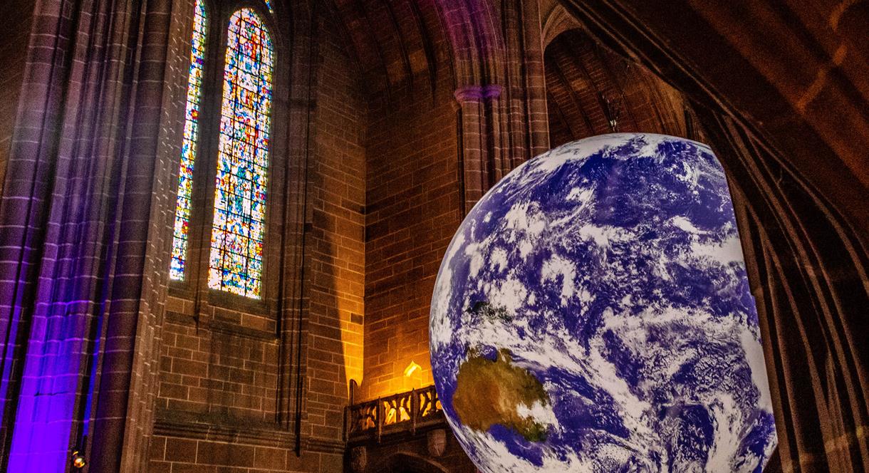 Image shows a huge model of Planet Earth, suspended from the ceiling of a Cathedral