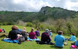 A group of walkers take a break, looking over at Thor's Cave in Staffordshire