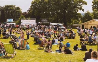 A host of great food stalls, with visitors relaxing in the sunshine, at The Trentham Estate, Staffordshire