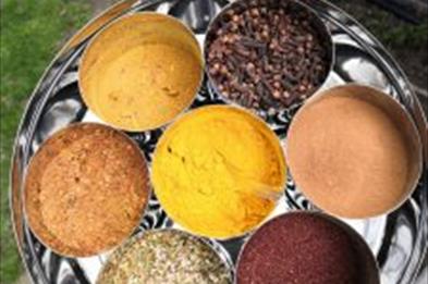 Photo shows a tray of different coloured spices in round containers