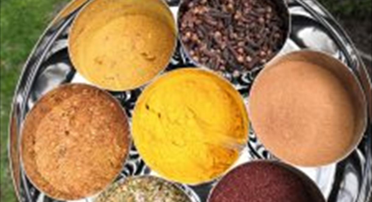 Photo shows a tray of different coloured spices in round containers