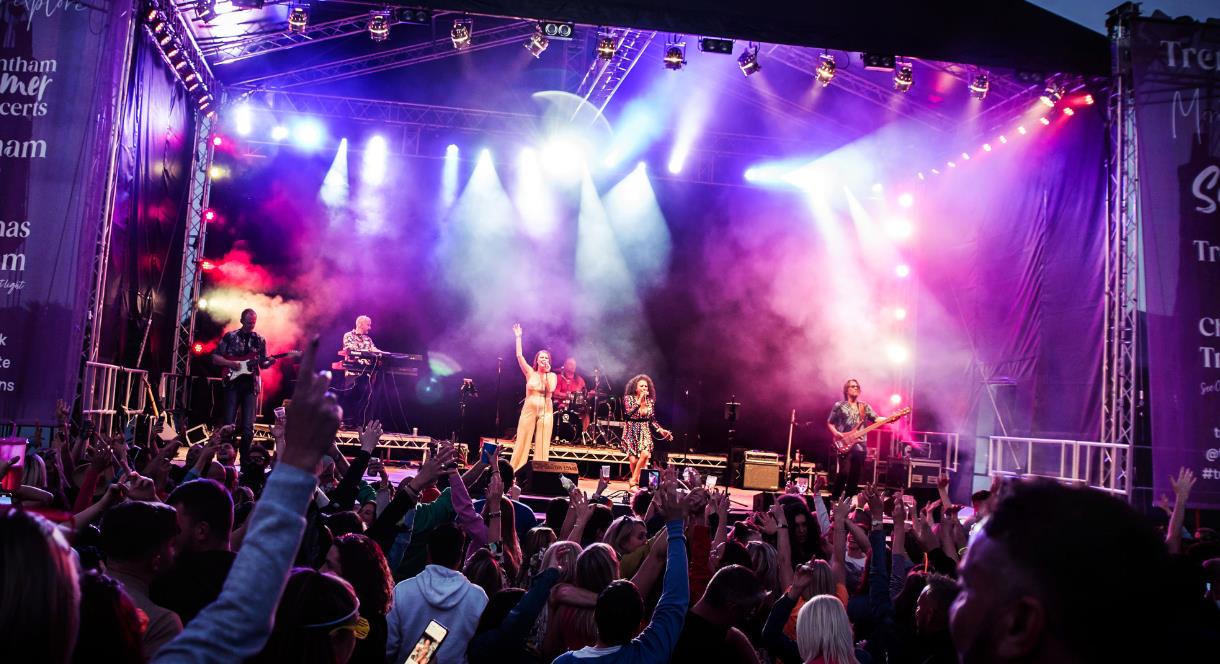Image shows a band performing on stage in front of a big crowd