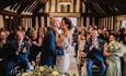 Image shows a couple kissing at the end of their ceremony, clapped by their guests, in the beautiful suite