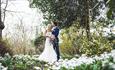 Image shows a bride and groom, posing for wedding photos in the woodland next to The Moat House