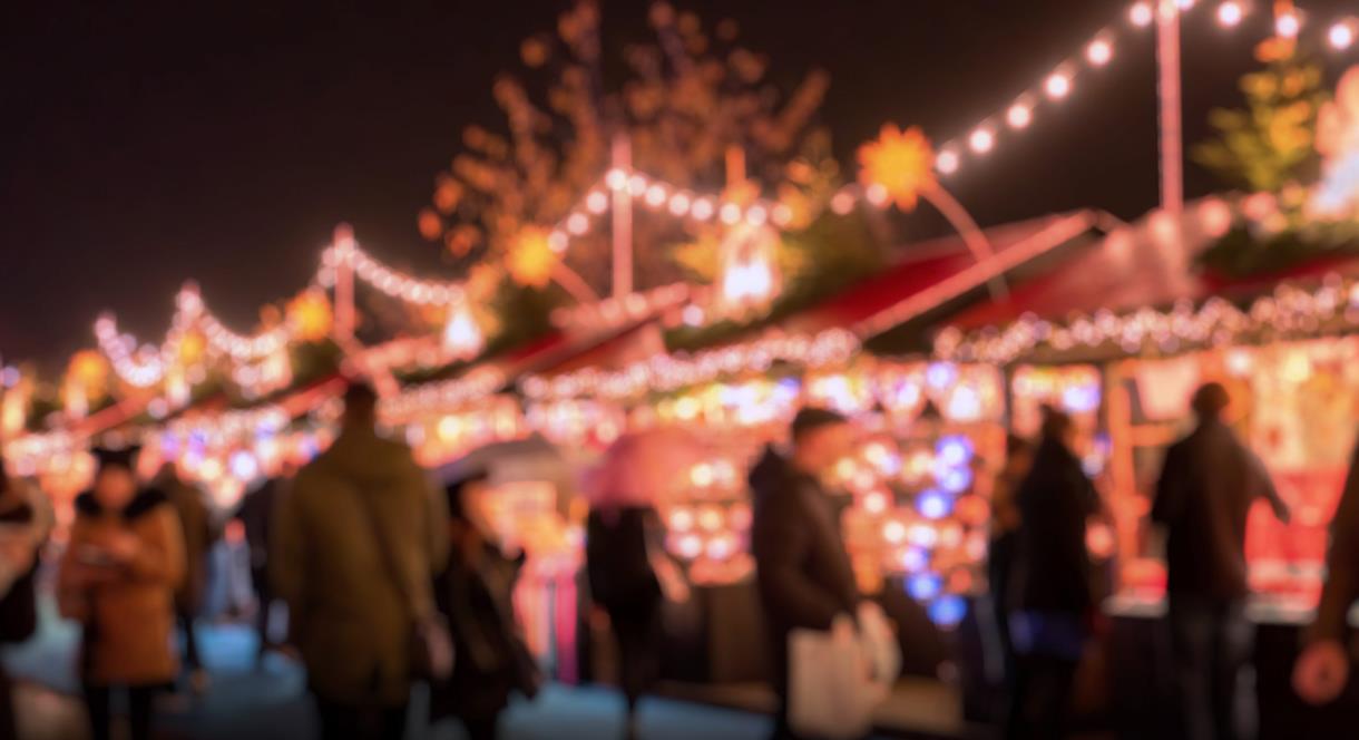 Image shows a market with Christmas lights and people browsing