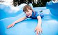 Image shows a young boy coming down a slide head-first