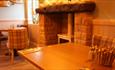 Image shows the welcoming interior of Ye Olde Rock Inn, with tables, chairs, a fireplace and a log-burner