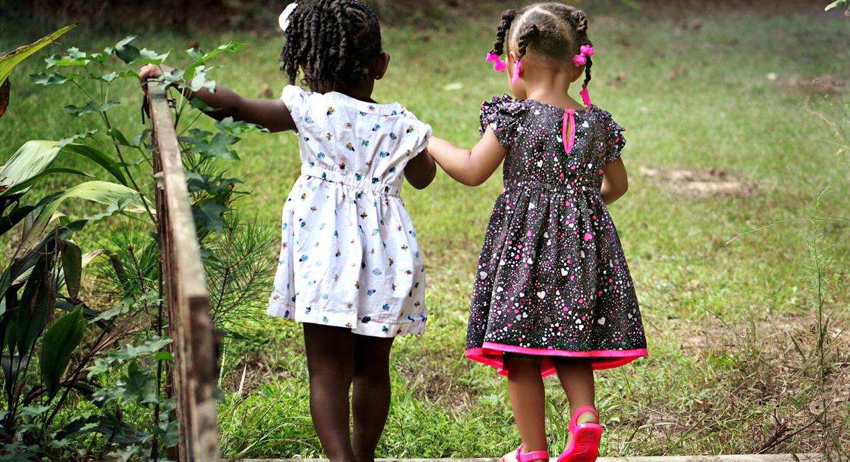 Two young girls crossing a bridge into a field